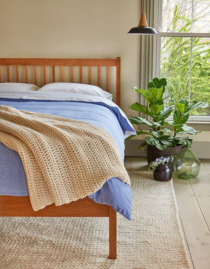 Bedroom with Chilton Furniture Co.'s solid cherry wood Falmouth bed, styled with cozy bedding and green plants