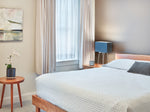 Neutral color bedroom with cherry furniture including round Mysa nightstand and Acadia live edge bed