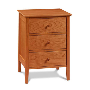 Simple Shaker nightstand with three drawers and tapered legs, in cherry wood, from Maine's Chilton Furniture Co.