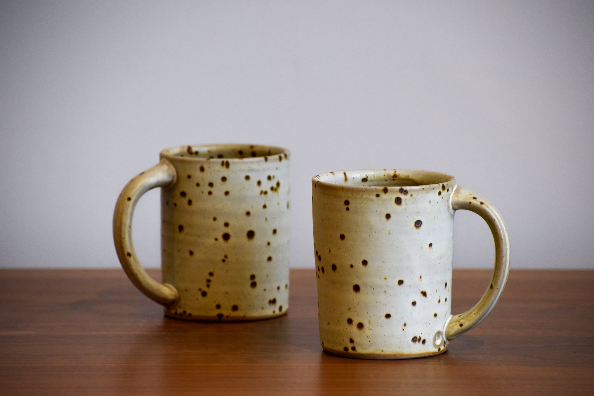 Two tall white ceramic mugs with dark spots