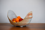 Large U shaped ceramic bowl, white and terracotta colored, with apples and oranges in it