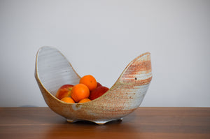 Large U shaped ceramic bowl, white and terracotta colored, with apples and oranges in it